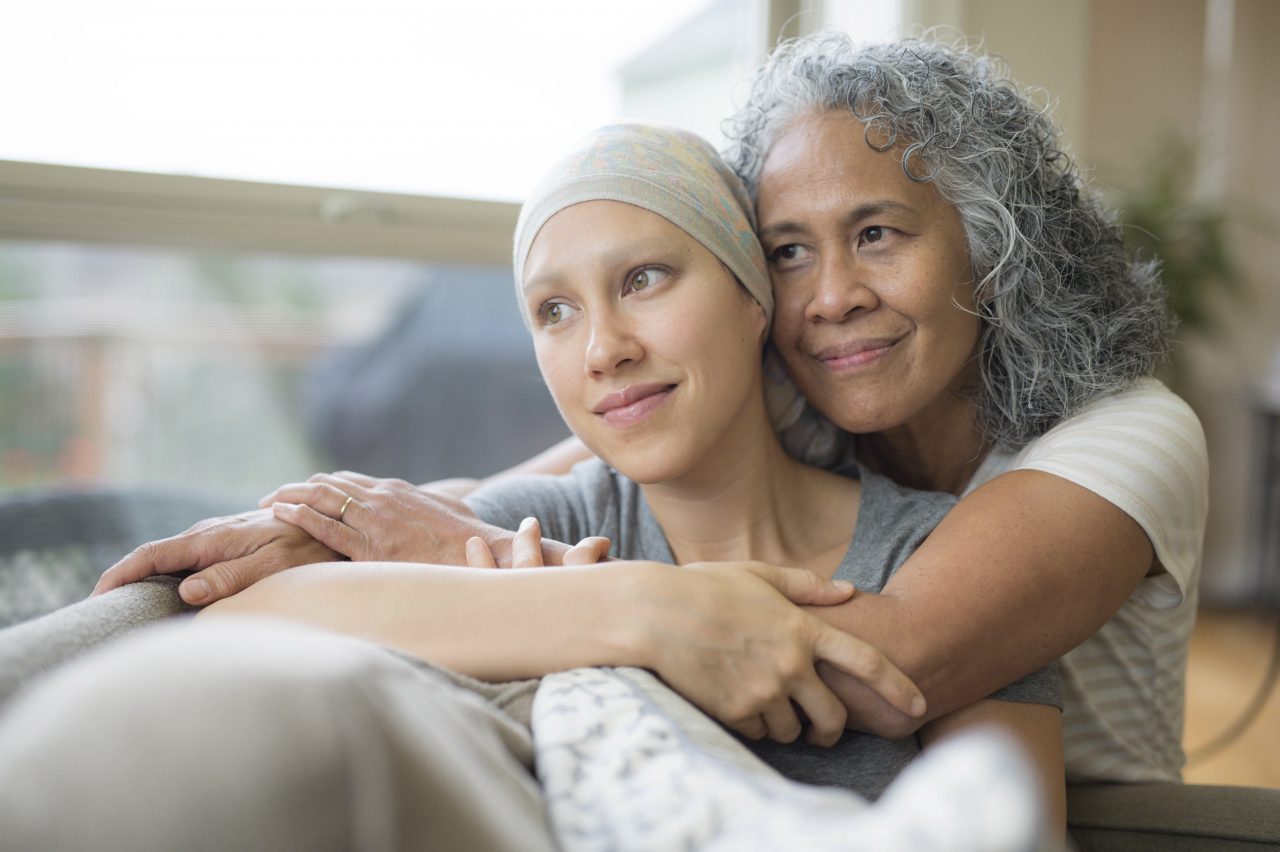 Young adult female cancer patient hugged by caregiver