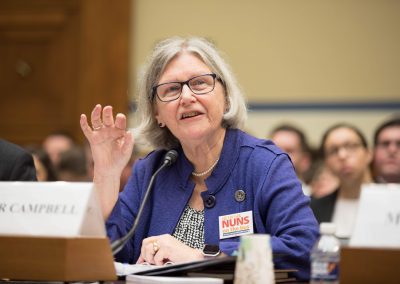 Sister Simone Campbell speaking on a panel before the House of Representatives Committee on Oversight and Reform. She is speaking and gesturing with her hands.
