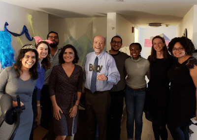 ESOI staff on Halloween. Eight people are smiling and looking at the camera. A few people are wearing costumes: crowns and animal ear headbands. One person is holding a sign that says "boo!"