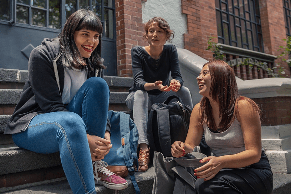 Three women sitting and talking on a porch