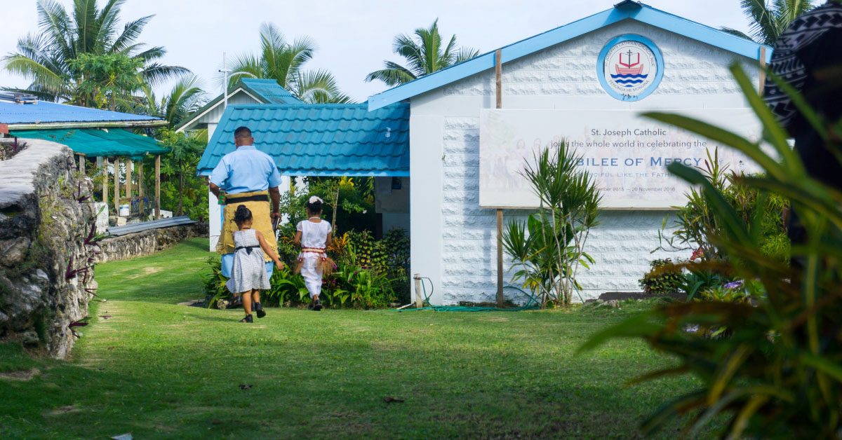 A father leading his two daughters to the entrance of a church