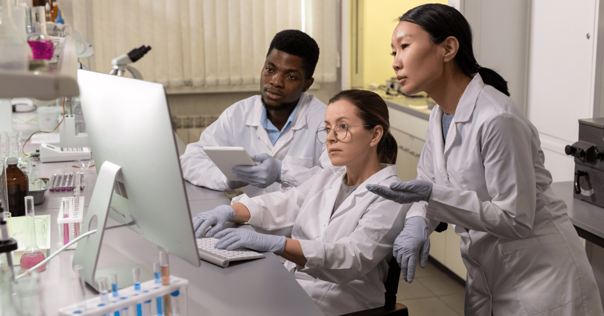 Three people working in a lab, looking at a computer monitor